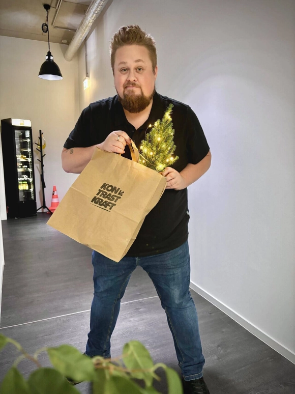 René von der Haar mit einer Tüte in der ein kleiner Weihnachtsbaum steckt